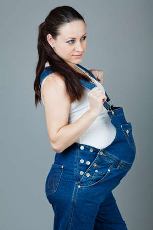 beautiful young pregnant woman in a dress with a gray backgroundの写真素材