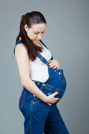 beautiful young pregnant woman in a dress with a gray backgroundの写真素材