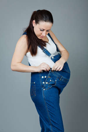 beautiful young pregnant woman in a dress with a gray backgroundの写真素材