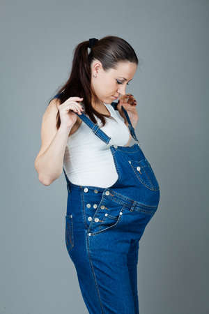 beautiful young pregnant woman in a dress with a gray backgroundの写真素材