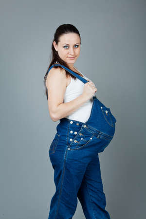 beautiful young pregnant woman in a dress with a gray backgroundの写真素材