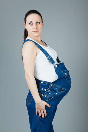 beautiful young pregnant woman in a dress with a gray backgroundの写真素材