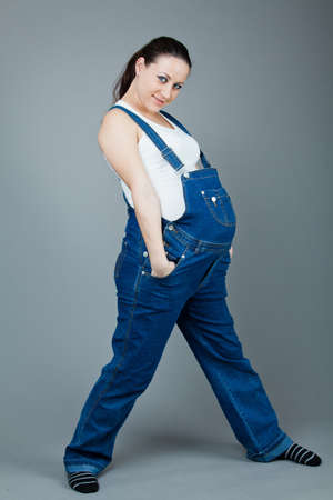 beautiful young pregnant woman in a dress with a gray backgroundの写真素材