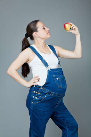 beautiful young pregnant woman in a dress with a gray backgroundの写真素材