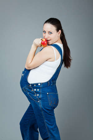 beautiful young pregnant woman in a dress with a gray backgroundの写真素材