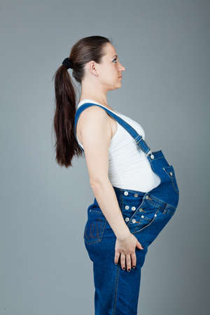 beautiful young pregnant woman in a dress with a gray backgroundの写真素材