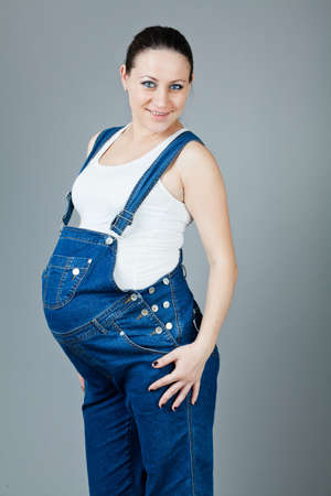 beautiful young pregnant woman in a dress with a gray backgroundの写真素材