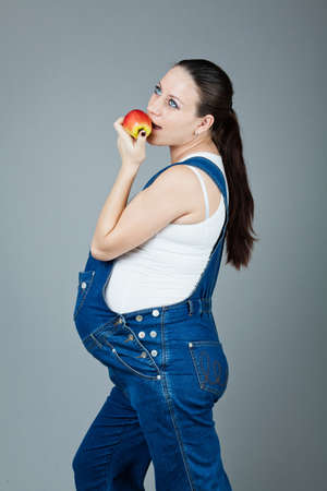 beautiful young pregnant woman in a dress with a gray backgroundの写真素材