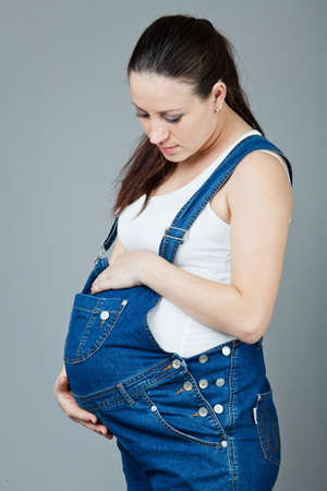 beautiful young pregnant woman in a dress with a gray backgroundの写真素材