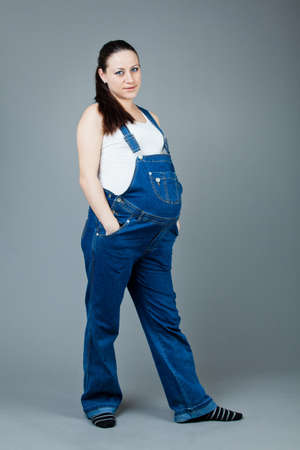 Portrait of pregnant brunette woman on grey background. young pregnant girlの写真素材