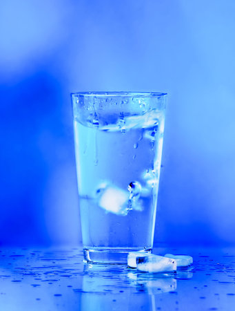 Glass of water on blue background  water with ice in glass
