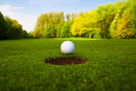 golf ball on lip of cup の写真素材