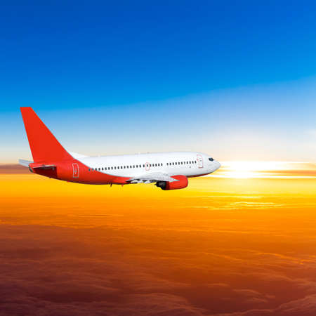 Airplane in the sky at sunset. A passenger plane in the skyの写真素材