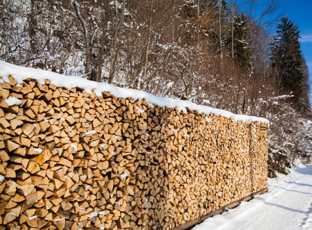 Firewood stacked in winter. Wood pile with snow stacked for firewood