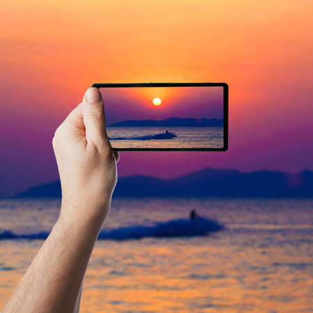 the jetski above the water at sunset.  Taking photo on smartphoneの写真素材