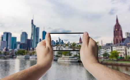 Hand with smartphone taken pictures of Frankfurt am Main skylineの写真素材