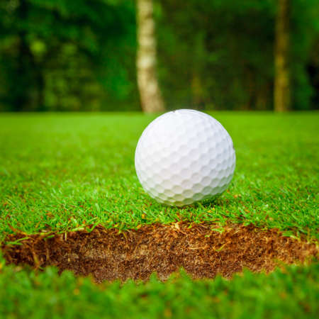 Golf ball on green meadow. golf ball on lip of cupの写真素材
