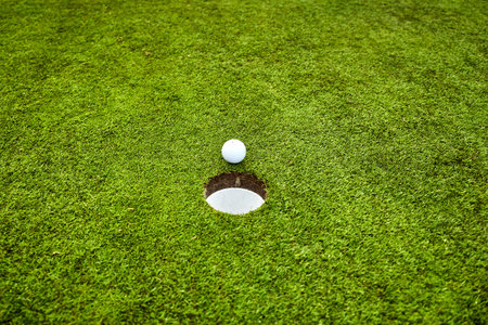 Golf ball on the green. golf ball on lip of cup