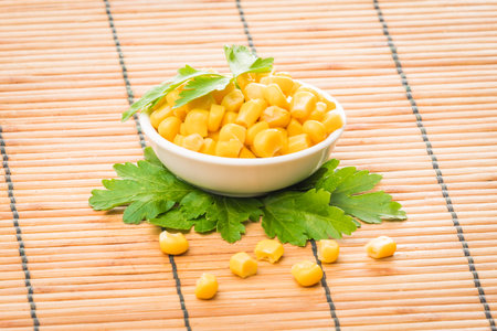 cooked sweet corn seeds in a  bowl on a wooden table. canned corn