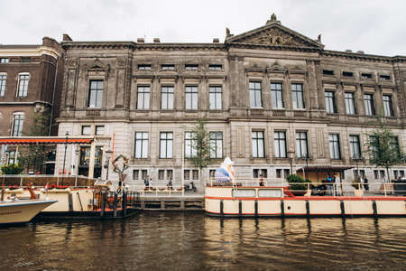 Amsterdam, Netherlands - September 5, 2017: A view along the Rokin Canal in Amsterdam during the day. Allard Pierson Museum, boats, Building and people can be seen.のeditorial素材
