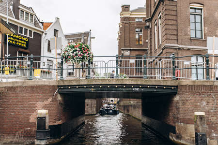 Amsterdam, Netherlands - September 5, 2017: Tour boat at famous dutch canal on a sunny day, surrounded by traditional old buildingsのeditorial素材