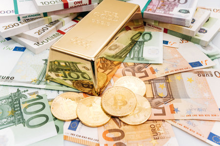 Bitcoin BTC Gold coins with bills of euro banknotes and gold bullion. Bitcoin and gold lie on Euro banknotesの写真素材