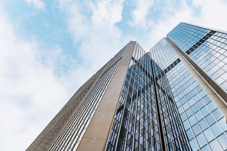 Bottom view of modern skyscrapers in business district against blue skyの写真素材
