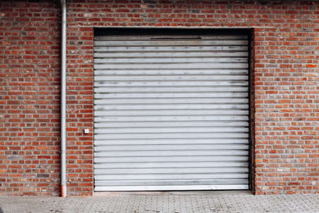 Large garage door with brick wall and asphalt drivewayの写真素材