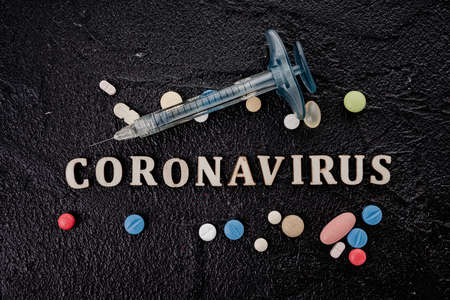 Coronavirus vaccine vial with injection syringe isolated on black backgroundの写真素材