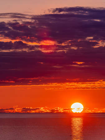 Red clouds sunset reflecting in waterの写真素材