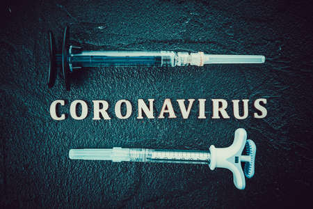 Coronavirus vaccine vial with injection syringe isolated on black backgroundの写真素材