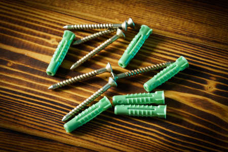 Closeup shot of a row of screws laid on a wooden tableの写真素材