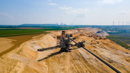 Aerial view of coal mine excavator with wind turbines in backgroundの写真素材