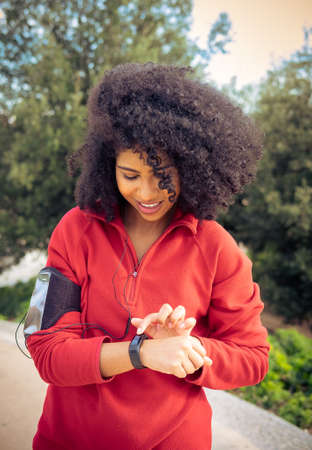Beautiful athlete woman preparing to run with earphones , smart watch and mobile app in the parkの写真素材