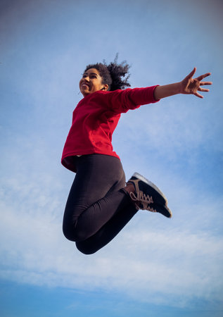 Beautiful athlete woman jumping happy after running in the parkの写真素材