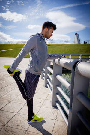 One young caucasian athletic man is preparing before running in a city park in winter.の写真素材