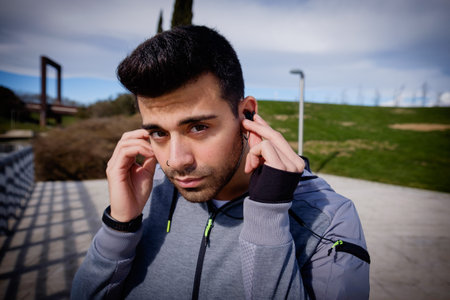 One young caucasian athletic man is preparing before running in a city park in winter.