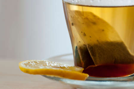 Glass cup of hot tea with tea bag and lemon sliceの写真素材