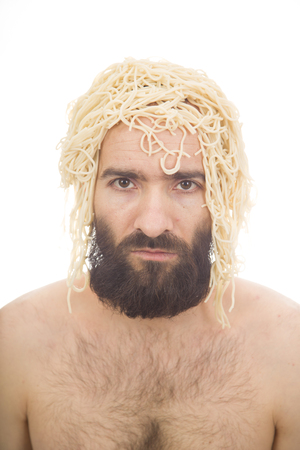 Bearded, funny, young man with spaghetti on his head. White background. Body without clothing. Portrait photo.Caucasian guy.の写真素材