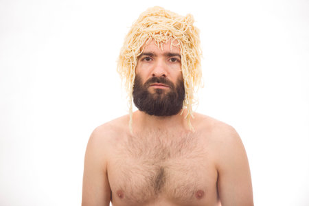 Bearded, funny, young man with spaghetti on his head. White background. Body without clothing....