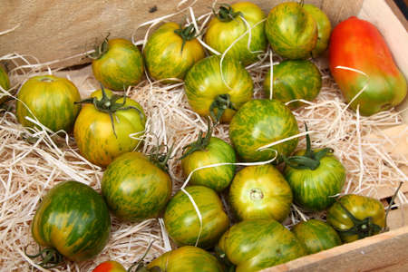 Green tomatoes in wooden box at market in Menton, town in South France, French rivieraの写真素材