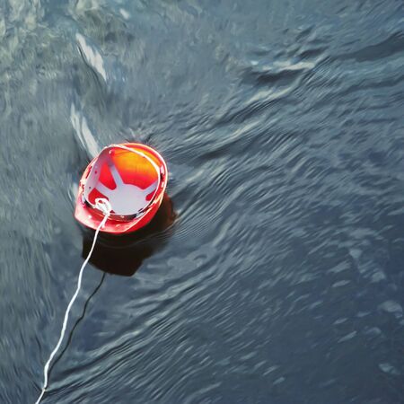 Construction helmet floating in the water, tied a cordの写真素材