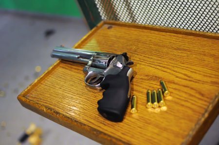 Revolver and bullets lies on the table at the shooting range room