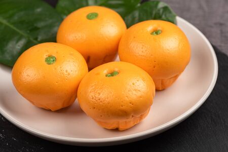 Cute pork buns in a form of oranges on white plateの写真素材