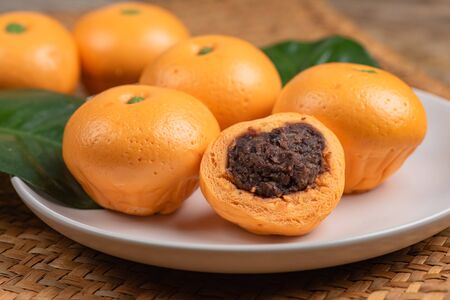 Cute pork buns in a form of oranges on white plateの写真素材
