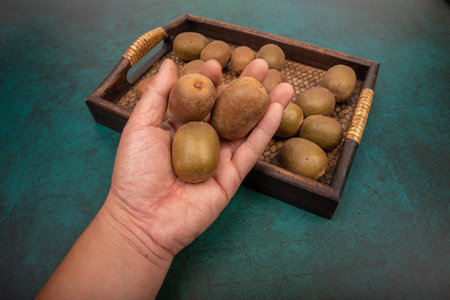 Kiwi fruit on a wooden flat plate against a dark green backgroundの写真素材