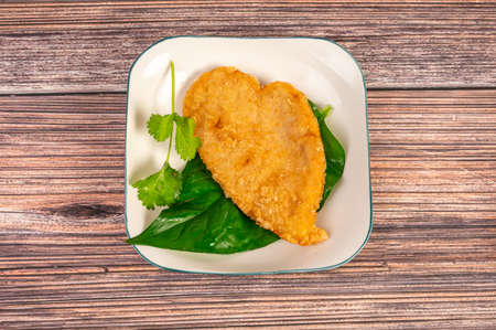 The fried food and green vegetables on the plate are on the wooden tableの写真素材