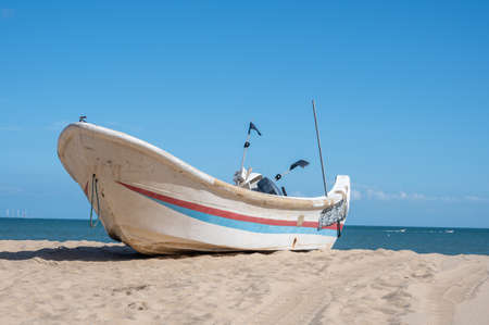 Striped boats docked on the beach, blue sky, sea and beachの写真素材