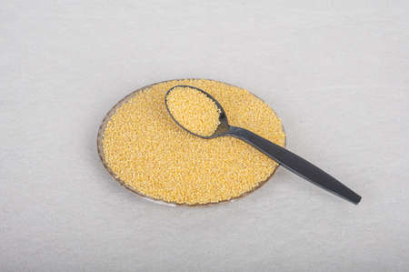 On a white background, a spoon is placed on the container containing milletの写真素材