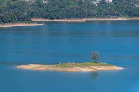 The shore of the lake is green, there are some small islands in the center, and the sky and water are blueの写真素材